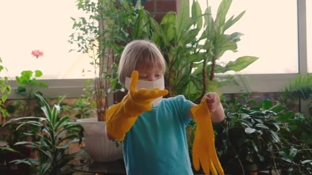 Niña linda en una máscara protectora y guantes de goma protectora — Vídeos de Stock