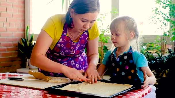 Eine glückliche Frau von 30 Jahren und eine kleine Tochter im Vorschulalter backen einen Kuchen. Lächelnde zweiköpfige Familie bereitet in einer modernen Küche gemeinsam selbst gebackenes Essen zu. — Stockvideo