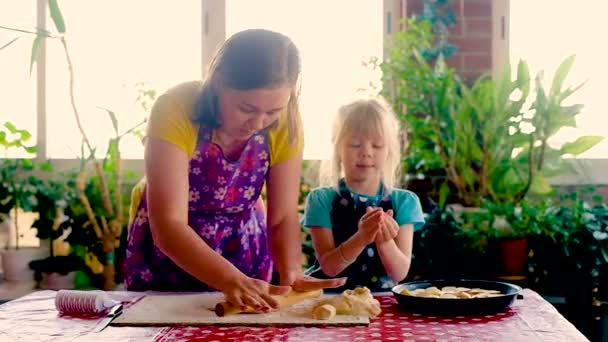 La donna felice di 30 anni e una piccola figlia di età prescolare cucinano una torta. Famiglia sorridente di due persone che preparano il cibo casalingo insieme in una cucina moderna . — Video Stock