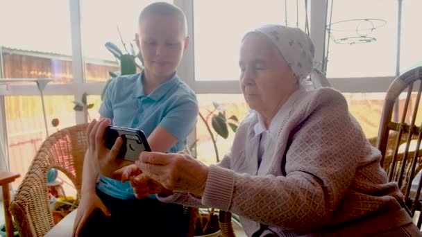 10 yaşındaki torun, 80 yaşındaki bir büyükanneye akıllı telefon kullanmayı öğretiyor. — Stok video