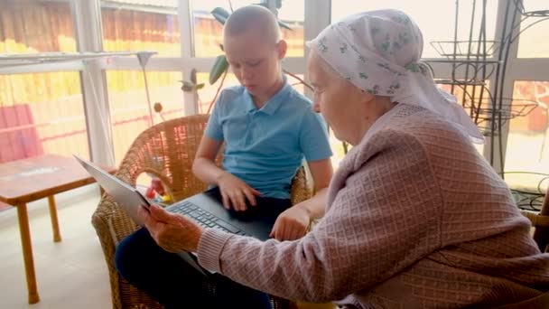 Nietos enseñan a 80 años de edad abuela a trabajar en un teléfono inteligente. jugando con un smartphone. Hacer compras en línea. son fotografiados. en la veranda de la casa. Comunicarse en Internet — Vídeos de Stock