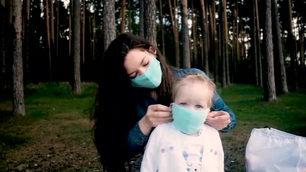 Junge Mutter setzt ihrer kleinen Tochter eine Schutzmaske auf. — Stockvideo
