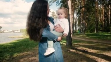 Küçük kızı olan genç bir anne parkta yürüyor..
