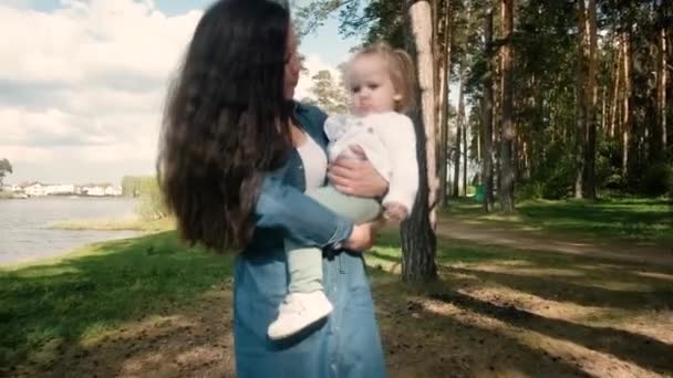 Νεαρή μητέρα με μια μικρή κόρη περπατούν στο πάρκο. — Αρχείο Βίντεο
