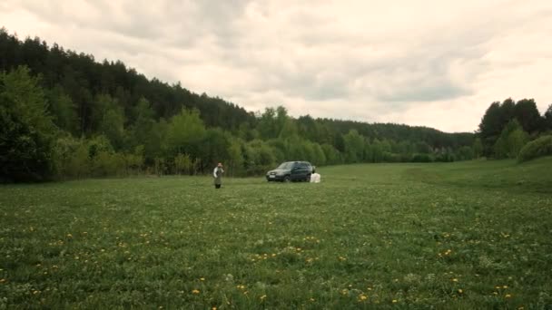 Strong man 60-65 years old with a scythe mows green grass on the field. — Stock Video