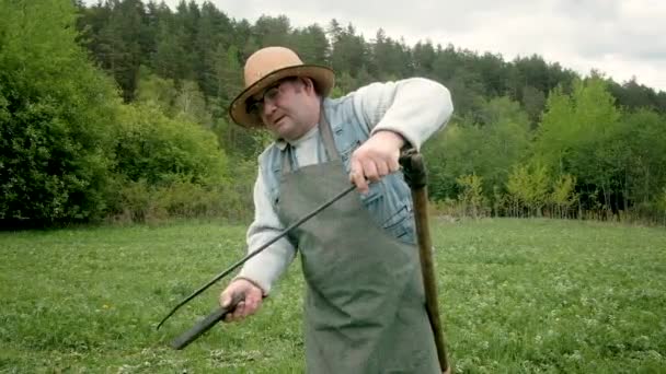 ブレイド・エメリーをシャープに。鎌を持つ強い男は緑の草を刈る — ストック動画