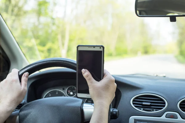 Kobieta kierowca z telefonu komórkowego w dłoni podczas jazdy. — Zdjęcie stockowe
