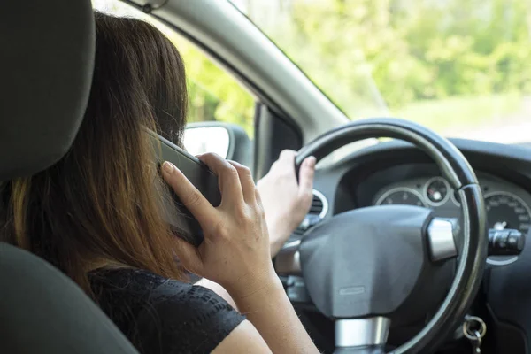 Women driver with a cell phone in hand while driving. — Stock Photo, Image