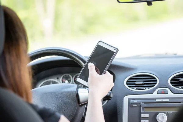 Women driver with a cell phone in hand while driving. — Stock Photo, Image