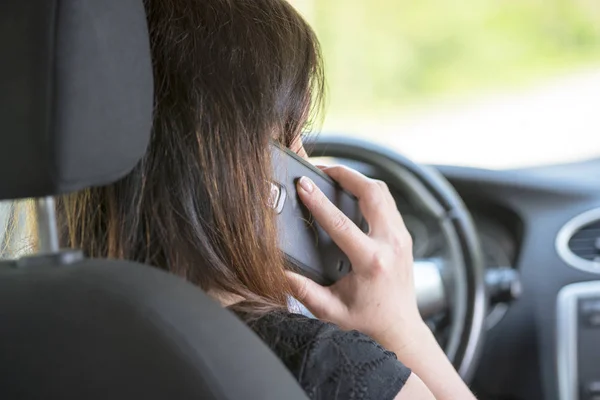 Women driver with a cell phone in hand while driving. — Stock Photo, Image