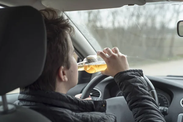 Joven conduciendo su coche mientras bebe alcohol —  Fotos de Stock