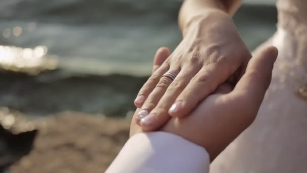 Bruden och brudgummen håller händerna nära upp på stranden — Stockvideo