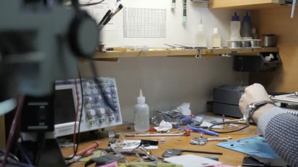 Человек ремонтирует сломанный смартфон в мастерской — стоковое видео