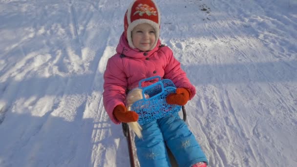 子供がそりに乗ってください。雪の中で外で遊ぶ子供たち. — ストック動画