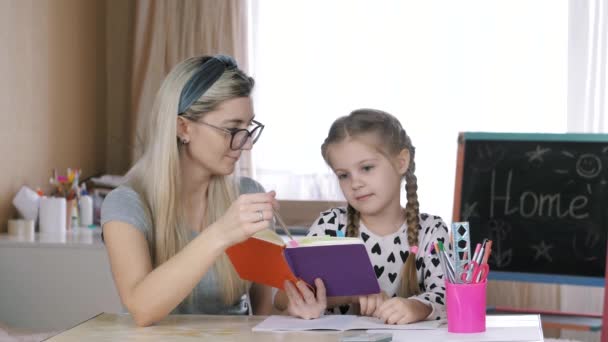 Mamá ayuda a mi hija a hacer la tarea, la repetición de los estudios . — Vídeos de Stock