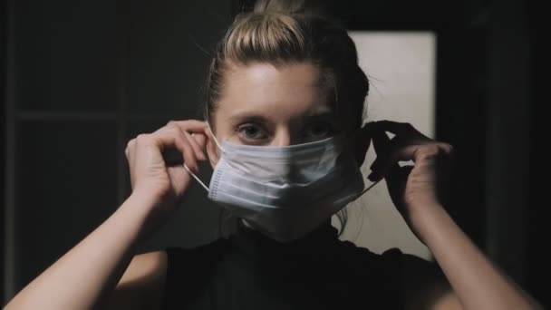 Frau setzt in der Dämmerung eine medizinische Schutzmaske auf. — Stockvideo