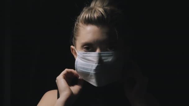 Pandemic Coronavirus. A woman who isolates at home puts on a protective mask to protect against the spread of the disease virus. Female mask, isolation on the face from coronavirus disease. — Stock Video