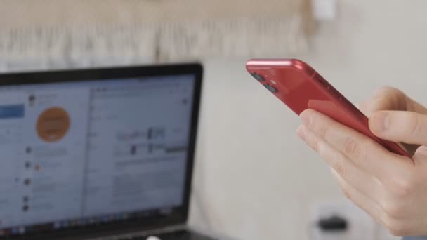 O homem no escritório tem um smartphone vermelho nas mãos. Scans, lê uma mensagem importante . — Vídeo de Stock