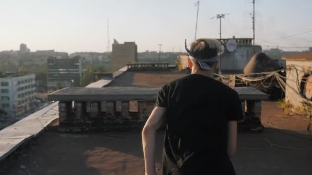 Parkour, een jonge man rennend op het dak van een oud hoogbouw bij zonsondergang. — Stockvideo