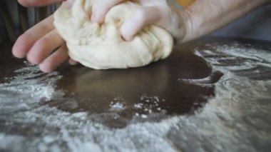 Kadın ahşap masada bir dilim taze maya hamuru yoğuruyor..