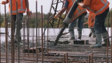 İşçiler binaya beton döşemiş, beton pompa inşaatta çalışıyor. İşçiler binayı beton bir karıştırıcı pompasından çimento harcı dökerek güçlendirdiler. Beton pompa inşaatta çalışıyor.