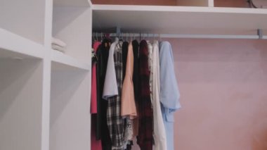 Kıyafetler gardıropta. Soyunma odasındaki askıda asılı giysiler, gömme dolaplar. Yeni, modern bir evde beyaz, dahili rafları olan gömme dolap..