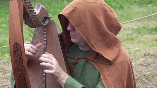 El festival anual Times and eras de reconstrucción histórica en Moscú, Rusia. Hombre tocando el arpa instrumento musical — Vídeos de Stock