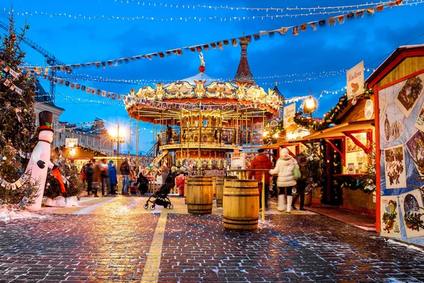 People on Christmas market on Red Square in Moscow city center, Decorated and illuminated Red Square for Christmas in Moscow. Carousel swings on Christmas bazaar — Stock Photo, Image