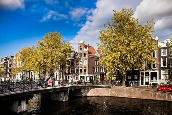 Solig vårdag i Amsterdam. Kanalutsikt med traditionella hus och cyklar, Nederländerna — Stockfoto