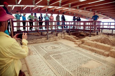 Yürüyüş ve antik döşeme mozaiği izlerken turistler. Kourion Kıbrıs güneybatı kıyısında antik kentinde yapıldı.