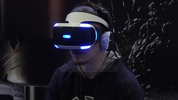 Hombre jugando juego de realidad virtual en auriculares Sony VR con controladores de accesorios en Sony stand — Vídeo de stock