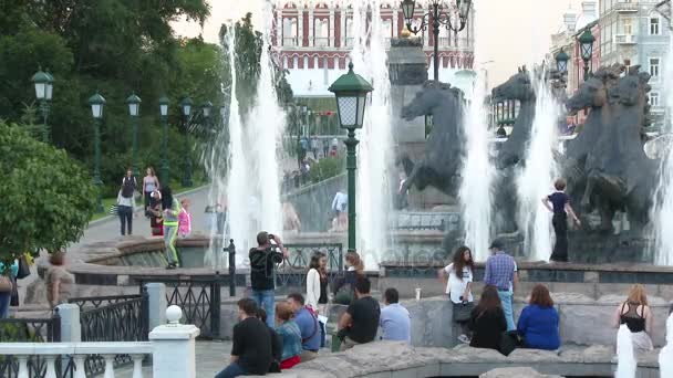 Gente caminando en Alexander Garden cerca de la Fuente Geyser por el escultor Zurab Tsereteli. La fuente Four Seasons con cuatro caballos en la plaza Manezhnaya en Moscú, Rusia — Vídeos de Stock