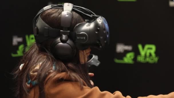 Menina jogando jogo de realidade virtual em HTC Vive VR fone de ouvido com controladores de acessórios — Vídeo de Stock