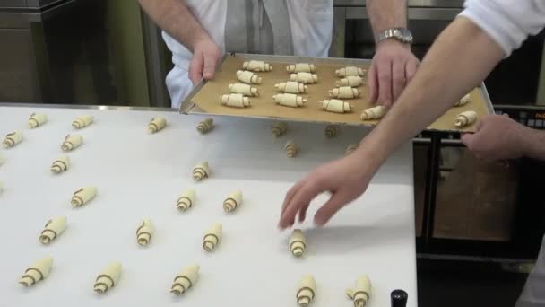 El hombre toma los croissants del transportador y los pone en la bandeja — Vídeos de Stock