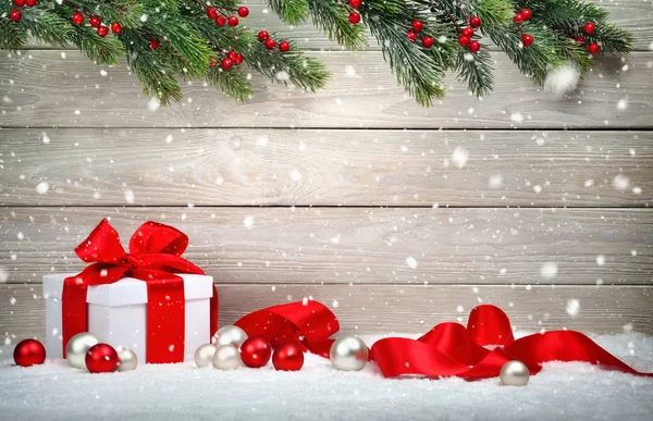 Christmas gift in snow, wood background — Stock Photo, Image