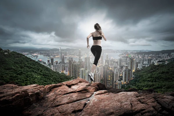 Menina fitness correndo sobre colina longe para a cidade — Fotografia de Stock