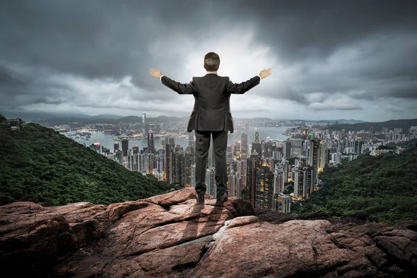 Businessman over hill with open arms — Stock Photo, Image