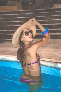 Hasır şapkalı, güneş gözlüklü, kameraya doğru yanıp sönen güzel bir esmer.