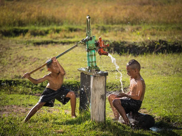 Dois meninos balançando banhos de água subterrânea nos dias quentes . — Fotografia de Stock