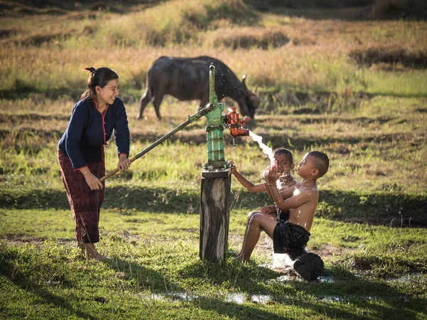 Mother her sons shower outdoor from Groundwater pump. — Stockfoto