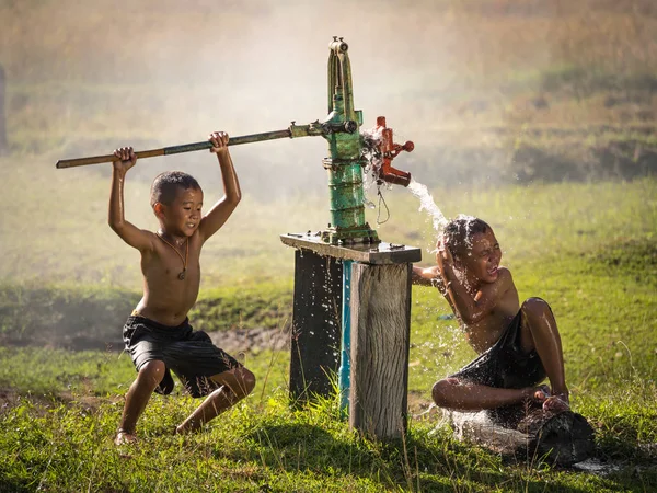Zwei kleine Jungen schaukeln Grundwasser in den heißen Tagen. Stockfoto