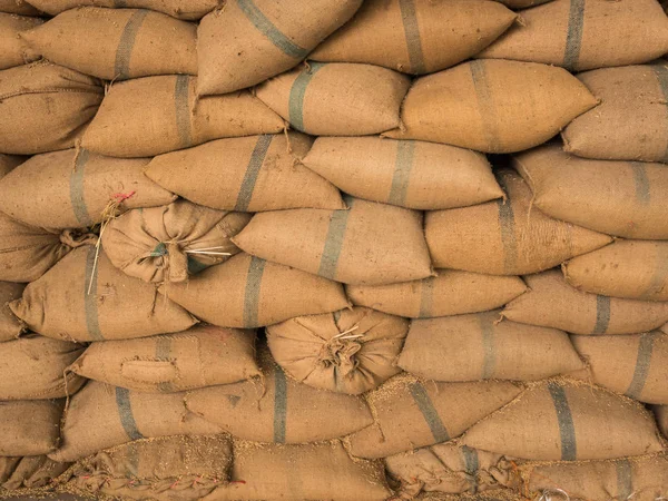 Sacos de cáñamo viejos que contienen arroz colocado apilado en una fila . — Foto de Stock