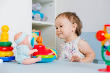 Küçük kız çocuk odasında eğitici oyuncaklarla oynuyor.