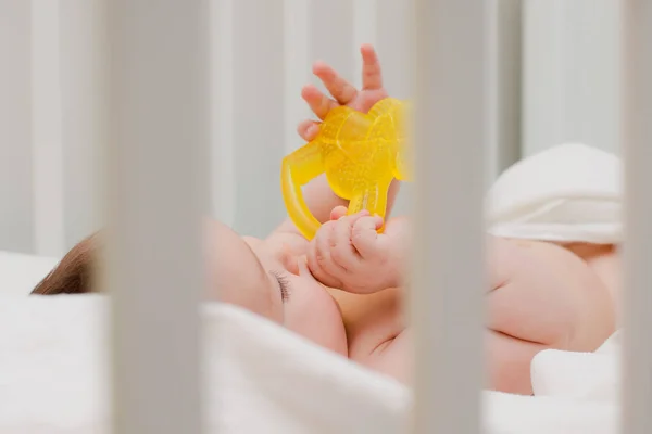 Baby in the crib gnawing teeth teether — Stock Photo, Image