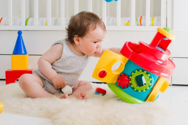 Bebê brincando com brinquedos educativos deitado — Fotografia de Stock