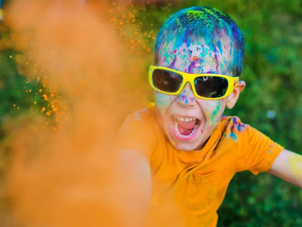 The child in glasses throws paint holi — Stock Photo, Image