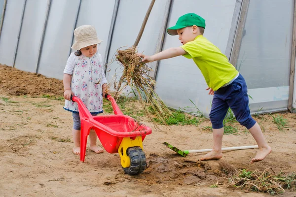 Kinder arbeiten im Garten mit Schaufel und Schubkarre — Stockfoto