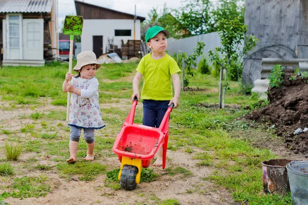 Kinder arbeiten im Garten mit Schaufel und Schubkarre — Stockfoto