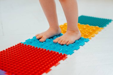 Bebek ayak masajı minderinde yeni yürümeye başlayan çocuk. Ortopedik masaj halısı üzerinde bacak egzersizleri. Düz taban ve halluks valgus önleme