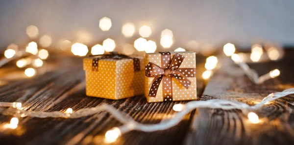 Kerstpakket doos lag op een houten tafel op een achtergrond bokeh van feestelijke verlichting. — Stockfoto